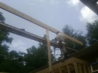 Carpenter setting a ridge beam over a new addition frame — Ice Dam Removal by Roofing Brothers in Lander
