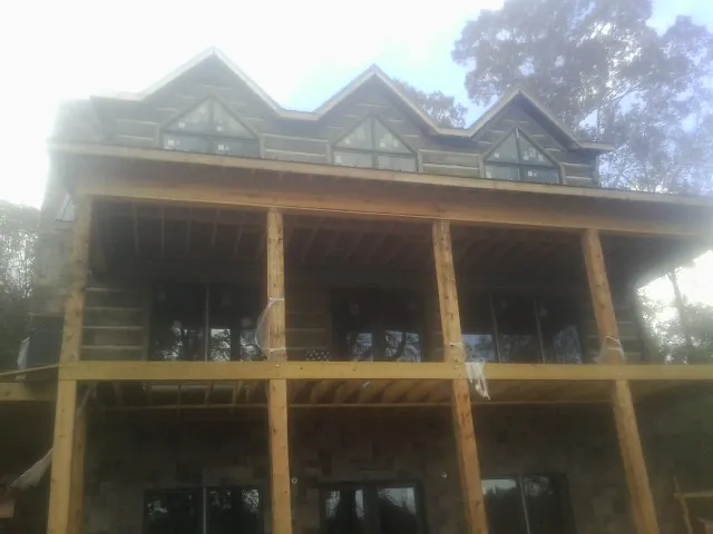 Dormers and porch framing on a large log home under construction — Roof Coating work by our crew in Lander