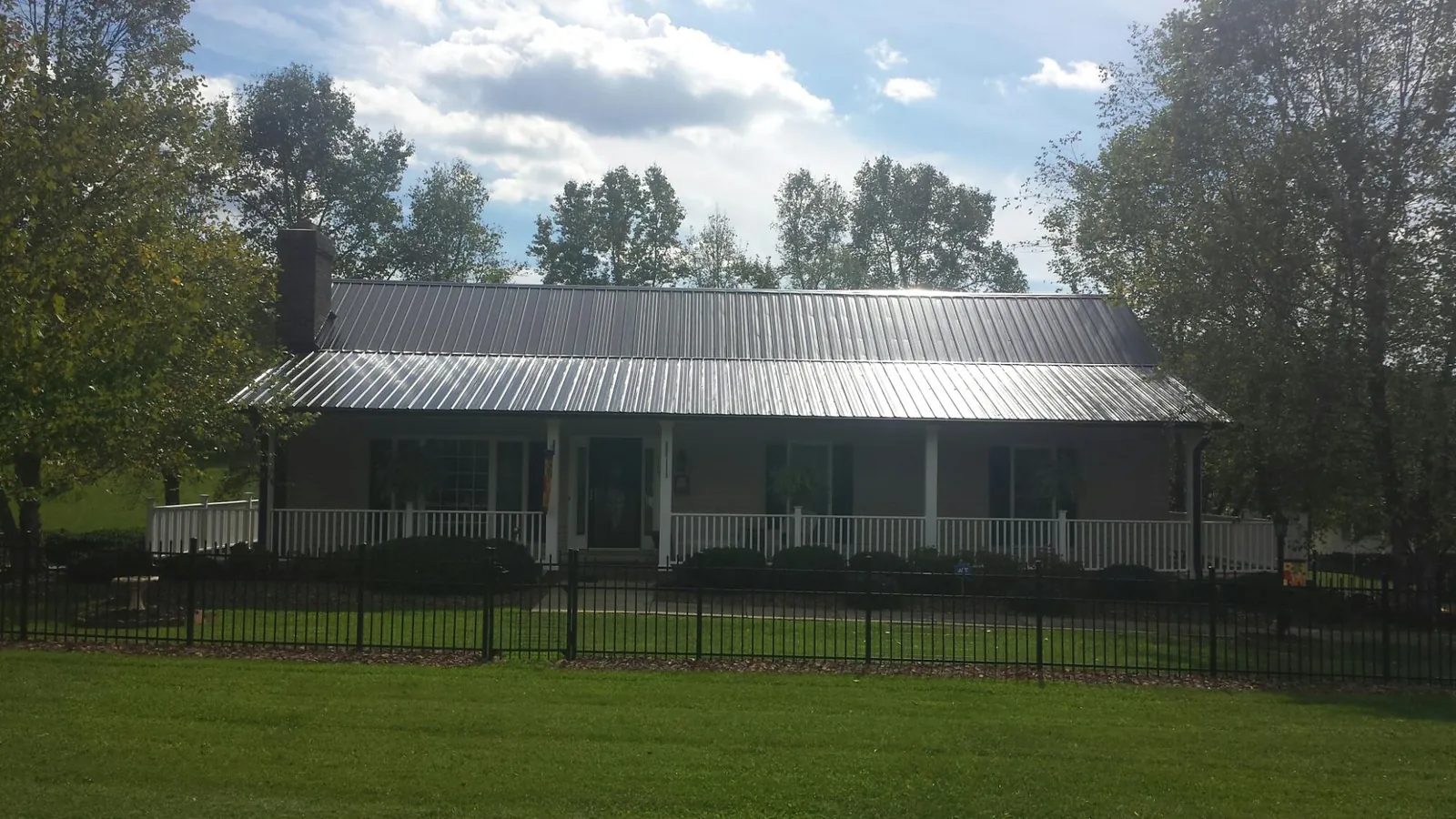 Gray metal roof on a brick ranch with a full width front porch — Gutter Guard Installation work by our crew in Lander