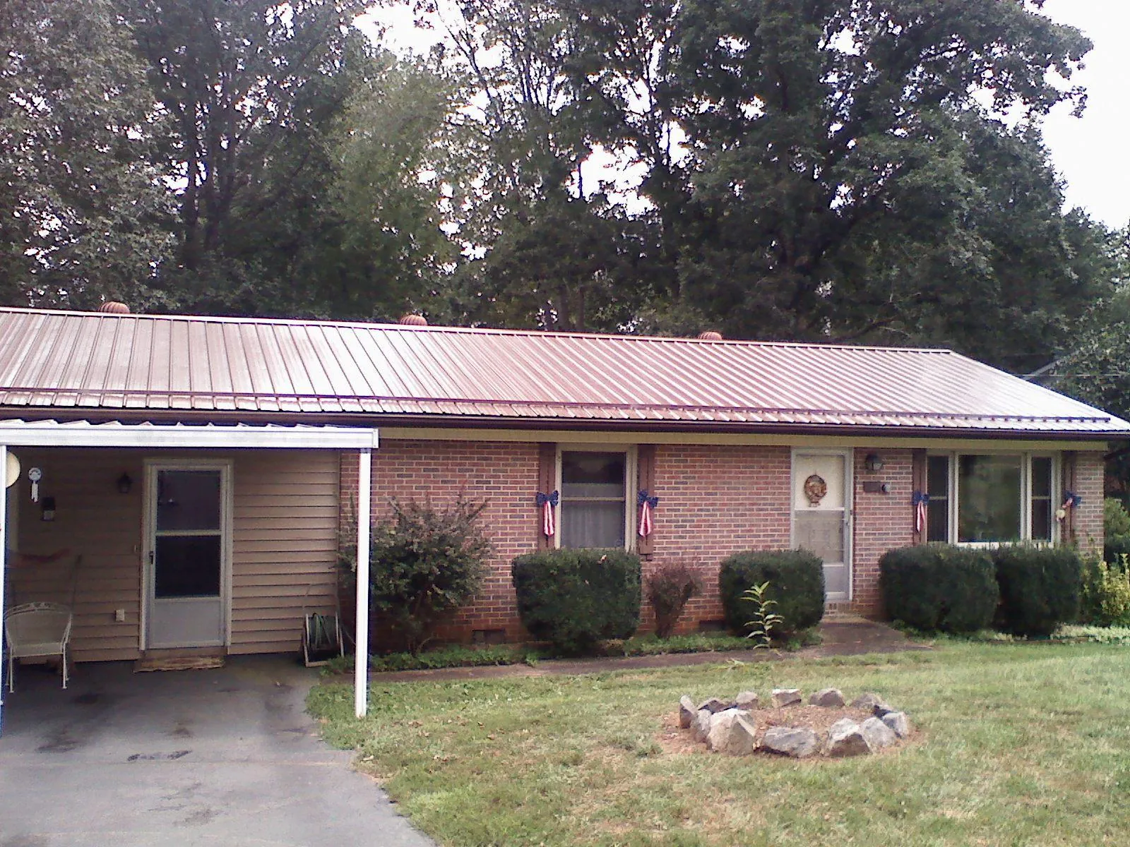 Bronze metal roof and carport on a brick ranch home — Roof Repair work by our crew in Lander