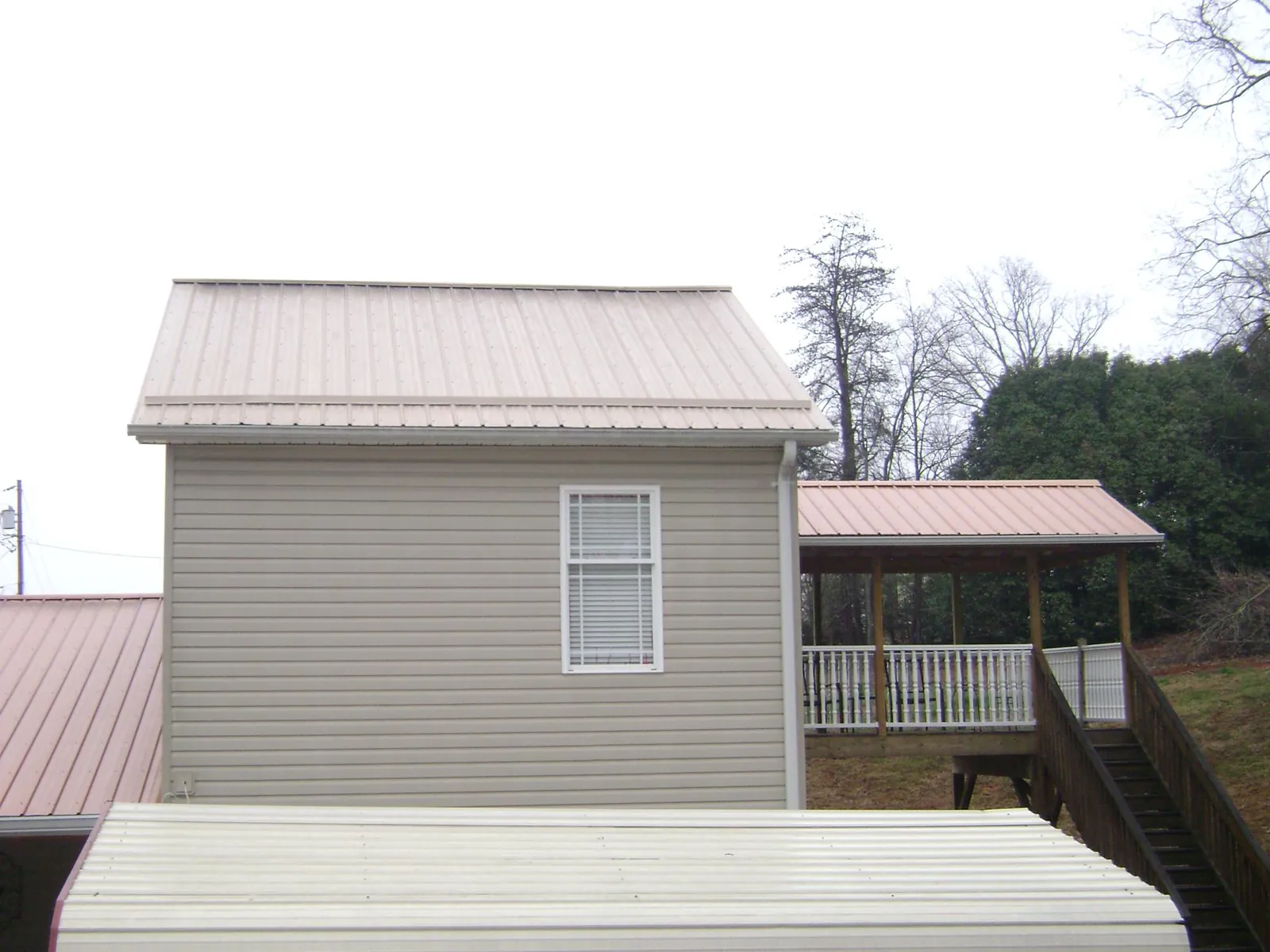 Tan metal roofs on a two story addition and attached porch, from a Roof Replacement job in Lander