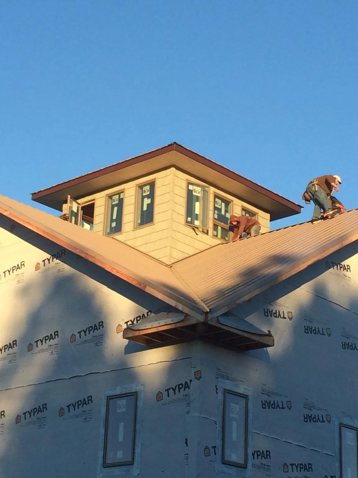 Roofers working around a rooftop cupola on a new metal roof at sunset — Roof Waterproofing in Lander by Roofing Brothers
